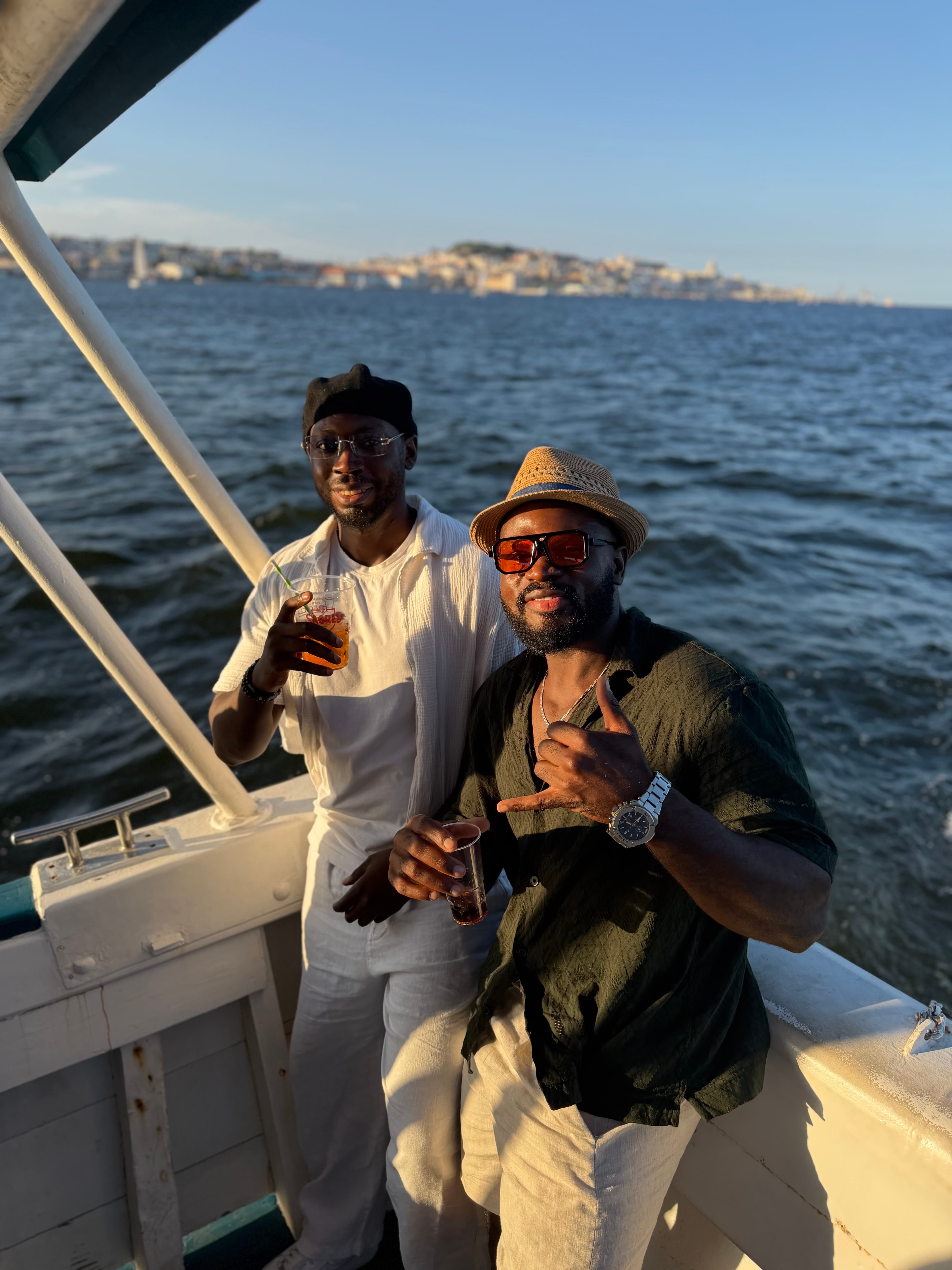 Dois convidados no barco com bebidas e Lisboa ao fundo