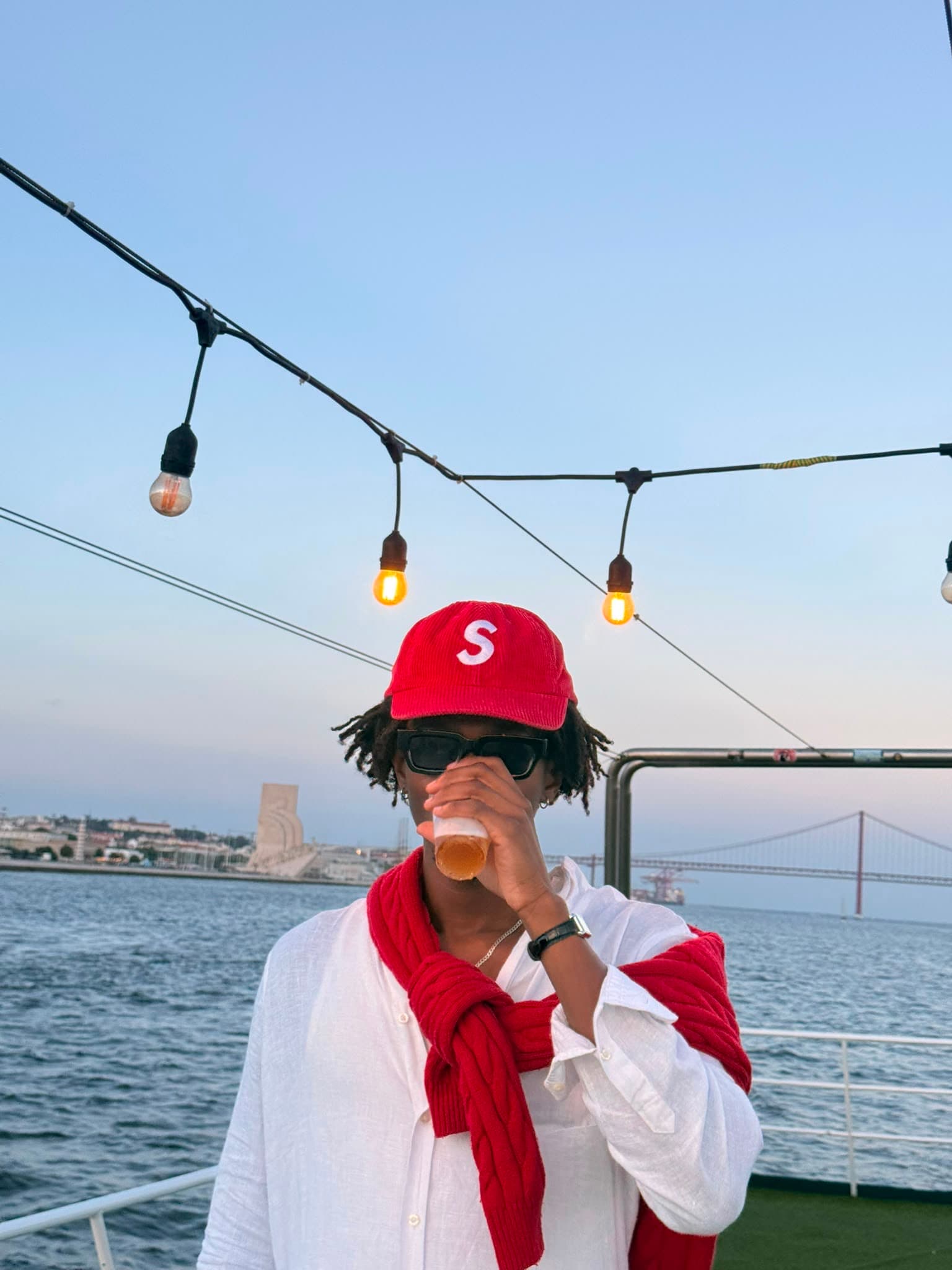 Convidado no barco com a Ponte 25 de Abril e a frente ribeirinha de Lisboa ao fundo